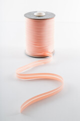 pink roll with a ribbon for clothes on a white background, soft focus