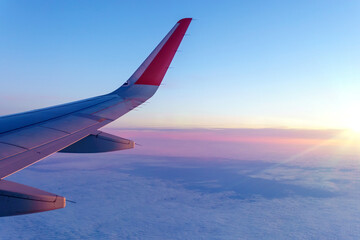 View of wing of an airplane flying above the clouds, morning time. The concept of the freedom journey