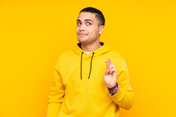 Asian handsome man isolated on yellow background keeps palm together. Person asks for something