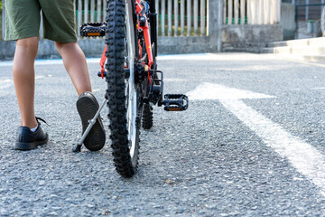 Close up of leg of a boy getting ready to ride his bike and move forward next to a white arrow sign...