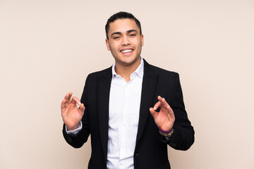 Asian business man isolated on beige background showing an ok sign with fingers