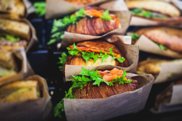 Beautifully decorated catering banquet table with different food snacks and appetizers setting with sandwiches, triange, croissant club submarine sandwich, on a wooden plate, on party or celebration