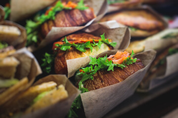 Beautifully decorated catering banquet table with different food snacks and appetizers setting with sandwiches, triange, croissant club submarine sandwich, on a wooden plate, on party or celebration