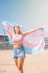 transsexual woman with trans flag, holding a transgender pride flag - obrazy, fototapety, plakaty
