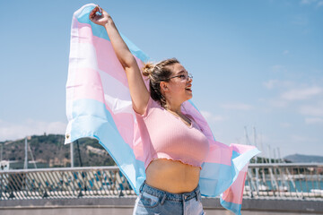 transsexual woman with trans flag, holding a transgender pride flag - obrazy, fototapety, plakaty