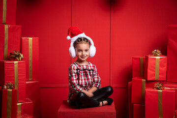 Hermosa niña latina con orejeras de navidad y con regalos muy feliz en fondo rojo