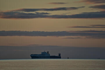 Beautiful centered early morning view of alone sea truck ferry ship in Irish Sea seen from Blackrock Beach, Dublin, Ireland. Soft and selective focus. Sunrise marine themed