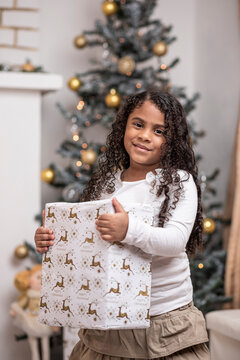 Hermosa niña afro caribeña disfrutando de la navidad con un árbol, adornos y regalos de fin de año