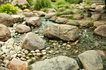 Stones in the landscape design of the park. Cobblestones in a mountain stream. Artificial pond with a waterfall.