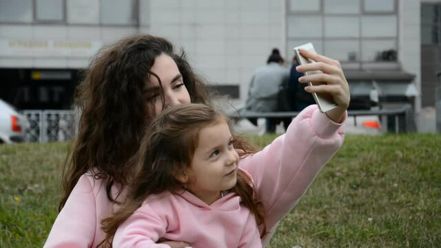 Photo selfie family caucasian mother and little child daughter hugging kissing shooting pictures via smartphone