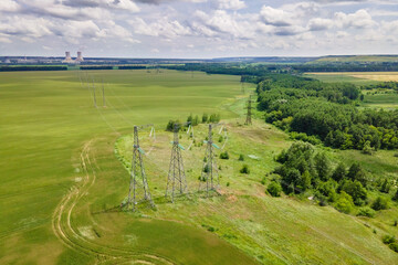 Transmission line in rural field. High-voltage tower for electrical grid in aerial view