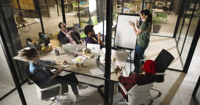 Group of diverse creative young people brainstorming and discussing strategies and ideas for project. Prosperous millennial colleagues analyzing in office high angle 4k footage
