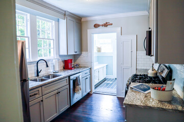 A small cottage kitchen with gray cabinets and dark hardwood floors in a short-term rental house