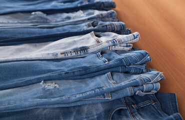 Fashion different jeans on wooden background.