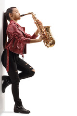 Full length profile shot of a young female in a leather jacket playing a saxophone and leaning on a...