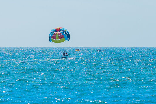 Ukraine, Iron Port - August 27, 2020: Extreme sports and exciting rest. A group of people with tourists on a motorboat with a parashut in the blue sea against the background of the horizon line