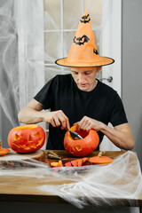 Man curving jac o lanten Helloween pumpkin at home. Getting ready for the holiday, 