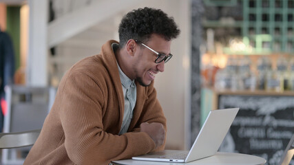 Successful African Man Celebrating on Laptop in Cafe 
