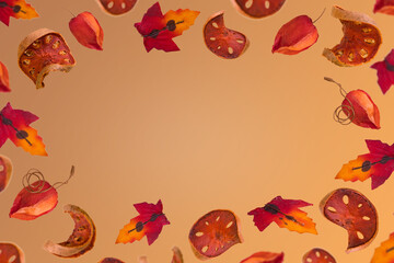 Obraz na płótnie Canvas Creative autumn frame with colorful leaves and sliced dried pumpkin on a orange brown background.
