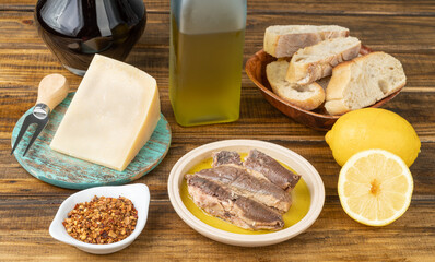Fish, cheese, olive oil, silician lemon, wine, pepper and bread over wooden table. Mediterranean food