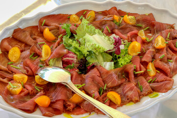 Tray of tuna carpaccio with cherry tomatoes and salad