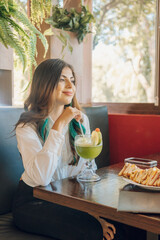 latin woman having fun with her boyfriend in a restaurant while drinks lemonade