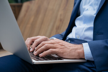 Closeup shot of businessman hands using laptop computer, typing on keyboard, searching information,...