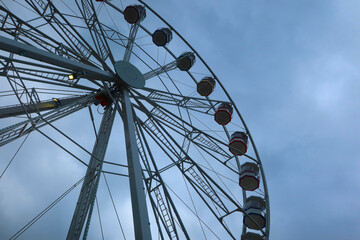 Ferris wheel spinning in an amusement park. Fairground ride.  Cabins of the ferris wheel. 