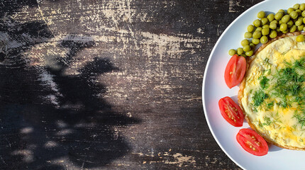 breakfast. omelet with vegetables on a white plate and a wooden background& omelet with cheese, dill, tomatoes and green peas