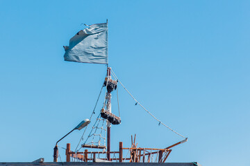 Flag on the ship sign and symbol of the sea cruise and adventure against the background of blue sky