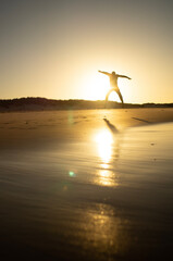 person jumping on the beach at sunset