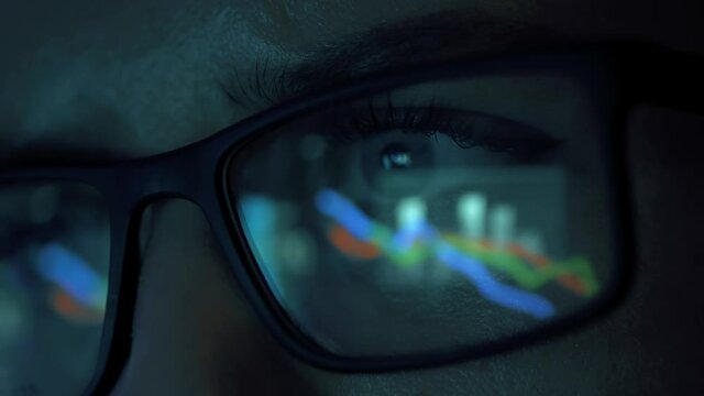 Portrait of woman working on laptop to research cryptocurrency financial markets. Trader or analyst wearing glasses. Analyzing btc stock market to make investment. Finance charts and graphs of crypto