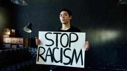 Young guy holding banner for protest, rally or awareness campaign against racial discrimination
