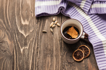 Autumn cozy composition. Cup of coffee, plaid, dried leaves on a wooden background. Autumn, fall concept. Flat lay, copy space