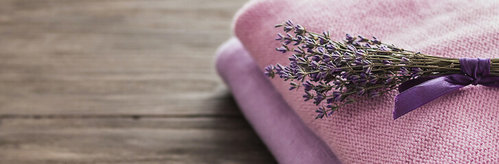Background with warm sweaters. Heap of knitted clothes and a bouquet of lavender on a wooden...