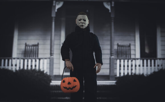 NEW YORK USA, SEPT 3 2021: Halloween slasher Micheal Myers with a trick or treat pumpkin pail outside the Myers house in Haddonfield  - Neca action figure