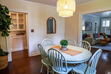 A small dining room with a statement rattan lighting ficture and a painted blue dining room table