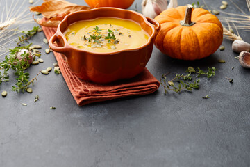 Pumpkin soup with thyme and pumpkin seeds on black background