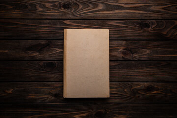 Closed book on vintage wooden back.  Old book on the wooden table. Closed book with empty cover...