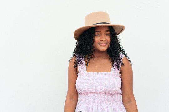 A pretty woman wearing a hat on a white wall