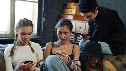 Obraz premium Group of diverse schoolkids stuck in mobile phones chatting online 