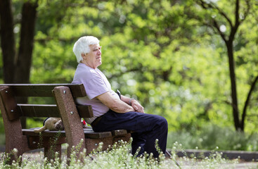 Fototapeta premium Pensive senior man sitting on bench in park