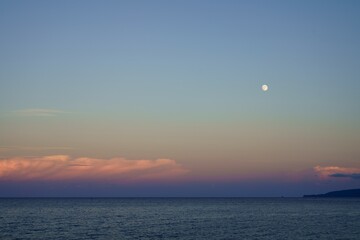島に沈む夕日と月