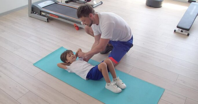Little boy training with coach in gym