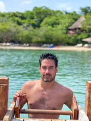Portrait of a handsome man in a paradise beach getting out of the water