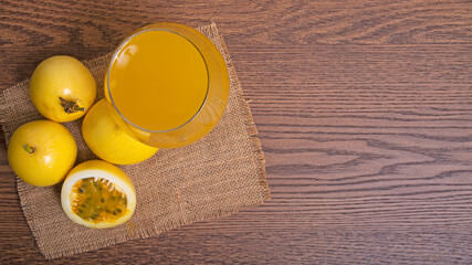 yellow passion fruit with glass of juice on brown wooden table