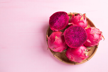 Ripe red dragon fruit or pitaya in bamboo basket on pink background, Tropical fruit