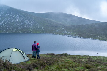Lake landscape. Tourists camping tent.. Young charming couple in love playing .Relaxing with...