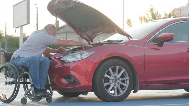 Disabled man in wheelchair check engine his car at parking