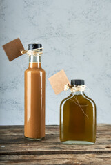 two bottles of artisan liquors onto wooden rustic table. grey background. horizontal